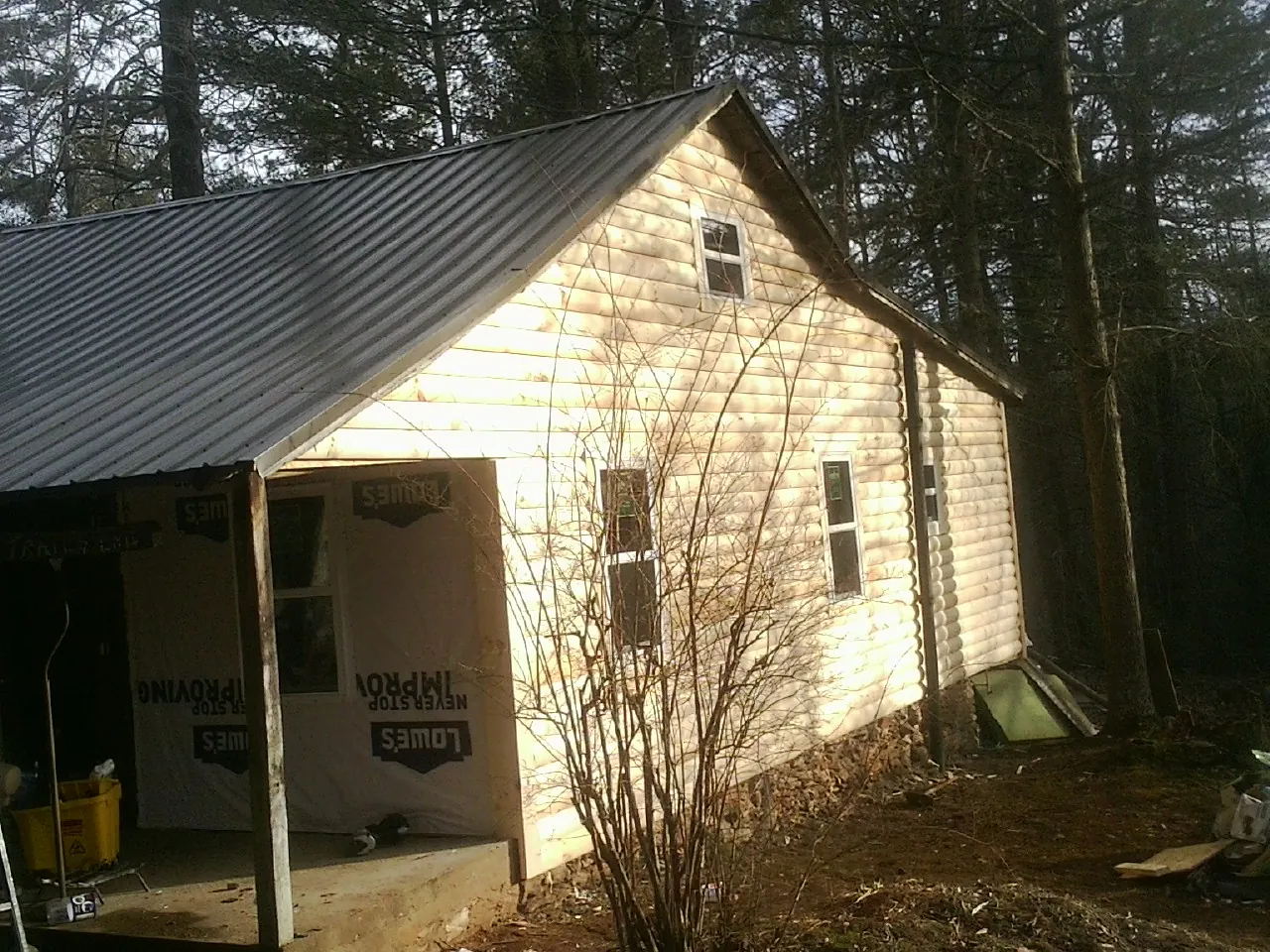 Log siding gable end under a dark metal roof edge in Hamilton